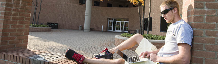 student on computer in front of Russ Engineering Building