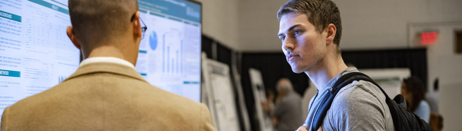 photo of a student and professor talking at a poster session