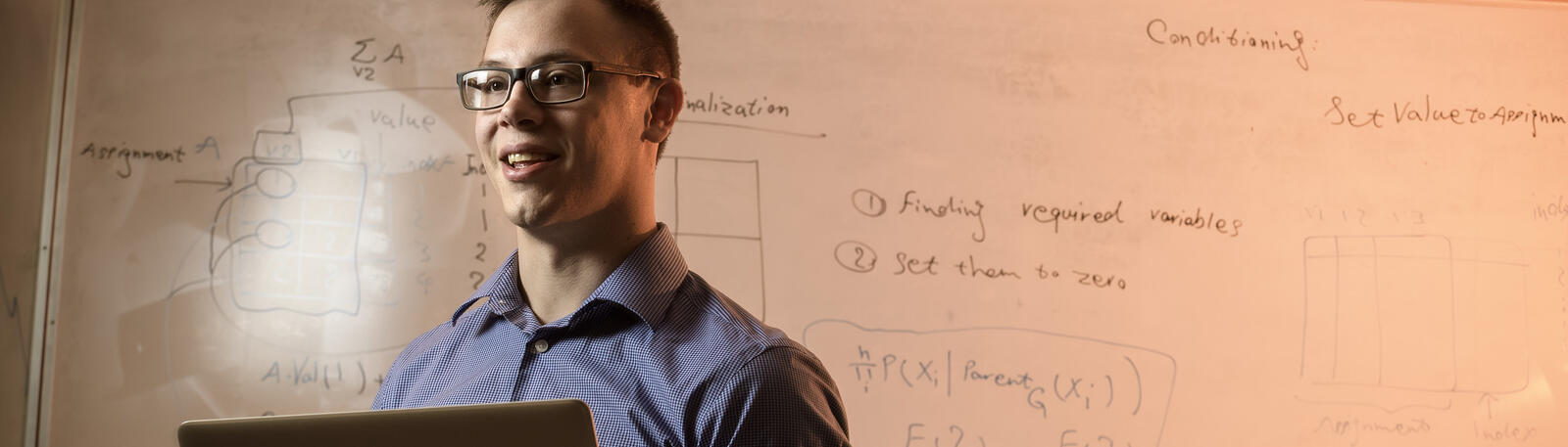 photo of a student with a laptop standing in front on a class