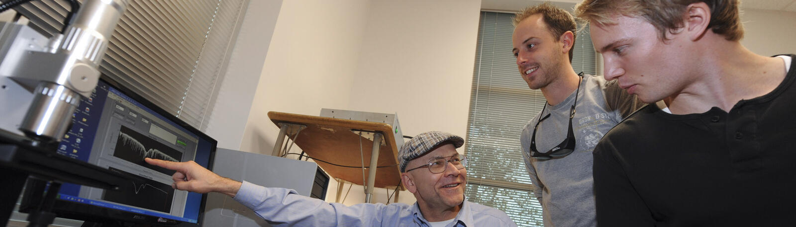 photo of a professor and two students looking at a monitor